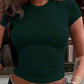 Woman wearing a fitted green crop top with short sleeves, paired with high-waisted jeans for casual fashion.