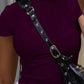 Woman in burgundy crop top with black studded crossbody bag, fashion outfit
