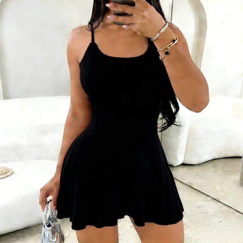 Woman in black sleeveless mini dress with flared skirt, holding silver handbag, stylish fashion outfit