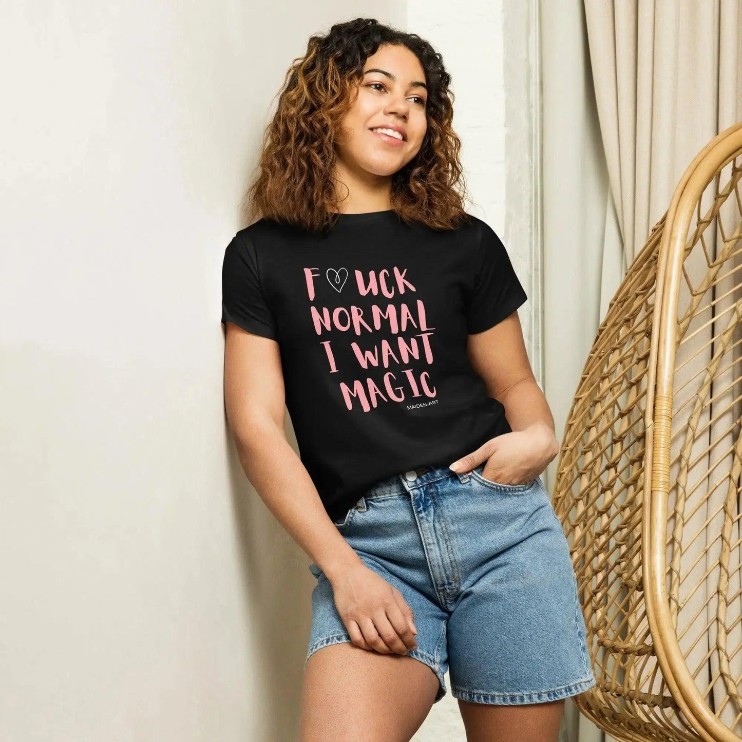 Woman wearing black graphic tee with pink 'Fuck Normal I Want Magic' text, denim shorts, casual fashion