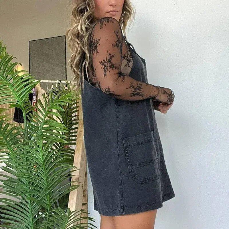 Woman wearing black lace long sleeve top under denim overall dress, fashion outfit