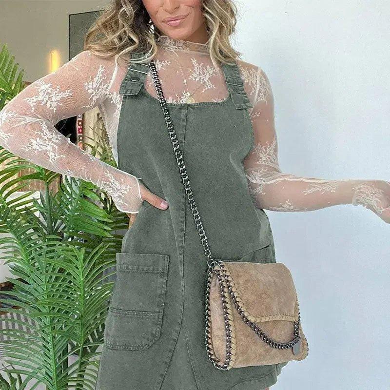 Woman in olive green denim overall dress with sheer lace top and chain strap bag, fashion style