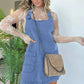 Woman in blue denim overall dress with lace top and chain strap bag, fashion outfit