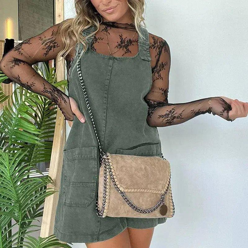 Woman in green corduroy overall dress with lace top, carrying chain strap suede bag, fashion outfit