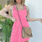 Woman in pink corduroy overall dress with lace top and chain strap bag, fashion outfit