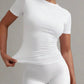 Woman modeling white fitted short sleeve top and matching leggings, stylish women's fashion outfit