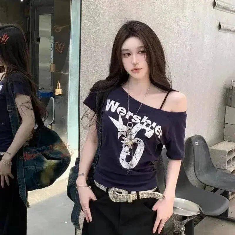 Woman in trendy off-shoulder graphic tee, black pants, and rhinestone belt — street style fashion