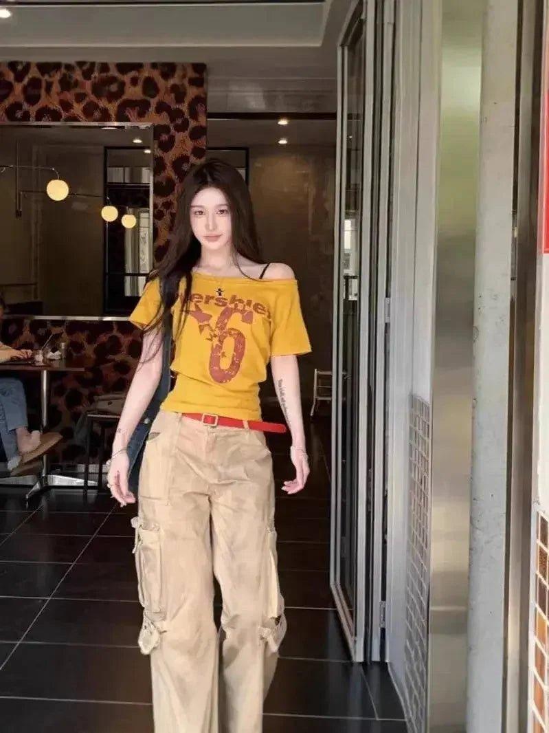Woman in yellow off-shoulder graphic tee and beige cargo pants, stylish streetwear fashion
