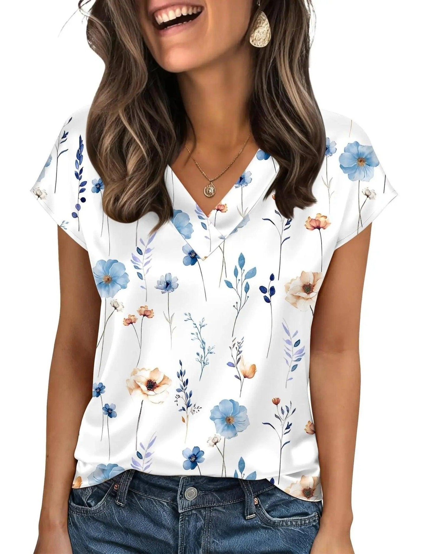 Woman wearing white floral print V-neck blouse with blue and peach flowers, paired with denim jeans