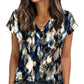 Woman wearing blue and white abstract print V-neck blouse with short sleeves, paired with jeans