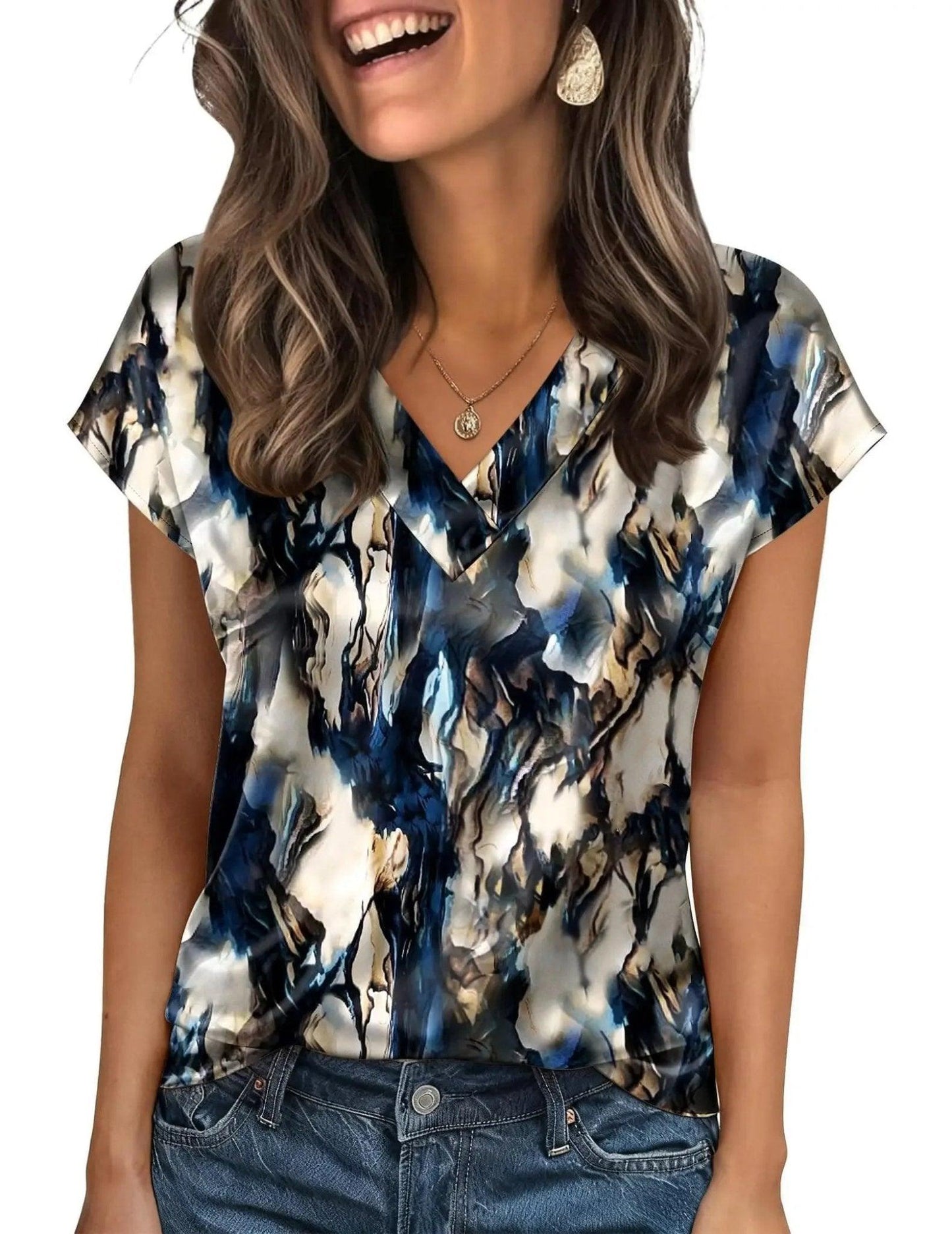 Woman wearing blue and white abstract print V-neck blouse with short sleeves, paired with jeans