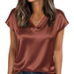 Woman wearing elegant satin V-neck top in rust color, paired with denim jeans, perfect for casual fashion.