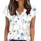 Woman wearing white floral print V-neck blouse with blue and peach flowers, paired with denim jeans