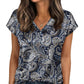 Woman wearing navy blue paisley print V-neck blouse with short sleeves, paired with jeans for casual fashion