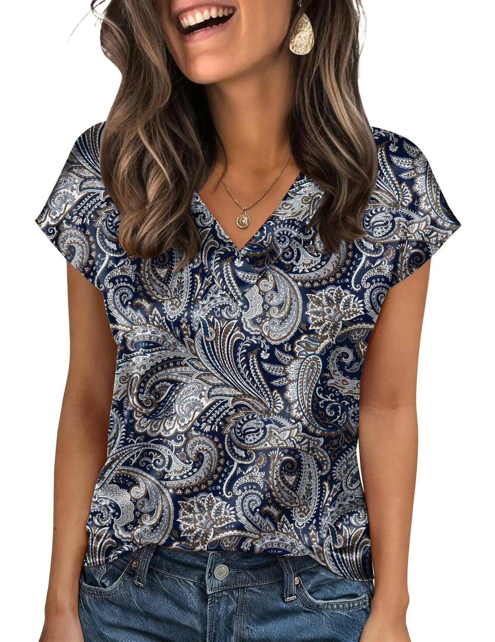 Woman wearing navy blue paisley print V-neck top with short sleeves, paired with jeans for casual fashion.