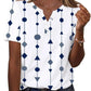 White women's geometric print V-neck t-shirt with navy blue shapes, short sleeves, and button detail
