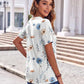 Woman wearing floral print blouse with blue and beige flowers, paired with jeans, outdoors near columns