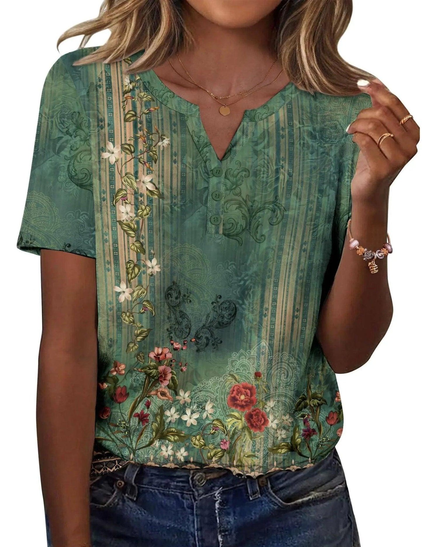 Green floral print women's V-neck blouse with short sleeves and button detail, paired with jeans