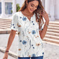Woman in white floral print V-neck blouse with blue and beige flowers, paired with jeans, outdoor fashion